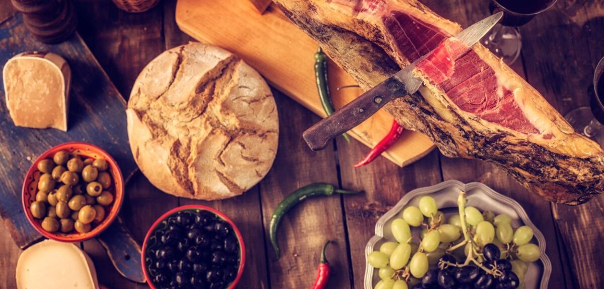 Jamon iberico su una tavola apparecchiata con frutta, pane e formaggio